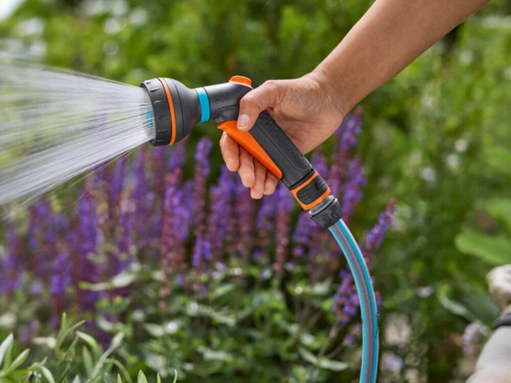 Pistolet zraszający GARDENA Classic 18370-20, obciążenie, blokada, naciskanie, trzymanie, dłoń trzyma pistolet w ogrodzie, polewający rabaty