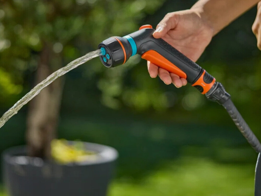 Pistolet zraszający GARDENA Classic 18375-20, impulsowe, blokada, wyzwalacz, kliknięcie, dłoń trzyma pistolet podłączony do węża z wodą