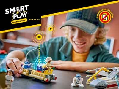 Osoba bawi się zestawem klocków LEGO, w tym pojazdem kosmicznym i figurkami. W lewym górnym rogu widoczne jest logo \'SMART PLAY\'.