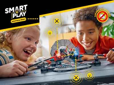 Dwoje dzieci bawi się zestawem LEGO na stole, na którym znajduje się model z serii Star Wars. W lewym górnym rogu widnieje logo \'SMART PLAY\' oraz napis \'media expert\'.