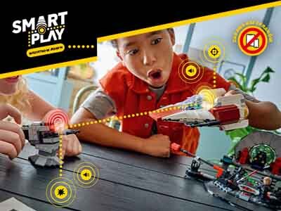 Dwoje dzieci bawi się zestawem LEGO na stole, trzymając modele statków kosmicznych. W lewym górnym rogu widoczne jest logo \'SMART PLAY\' oraz napis \'WYZWANIA W BUDOWIE\'.