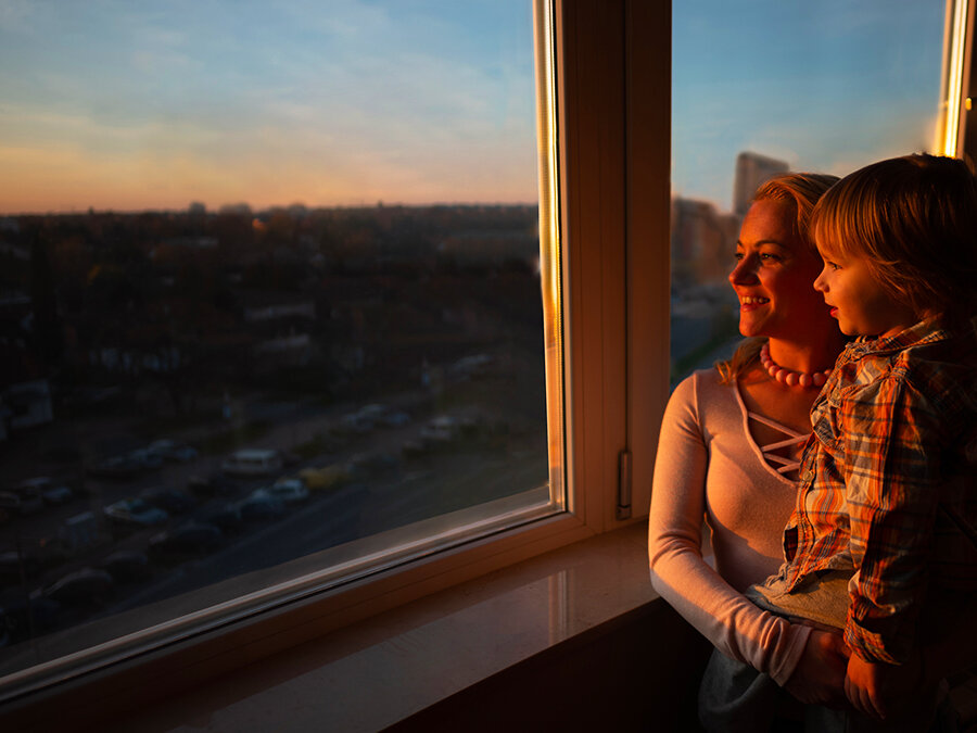 Widok z aparatu z funkcją wymazywania obiektu przedstawia matkę i syna wyglądających przez okno o zachodzie słońca. Zastosowano opcję AI Edit, a w miarę przesuwania się suwaka od lewej do prawej odbicie matki i syna w oknie jest usuwane.