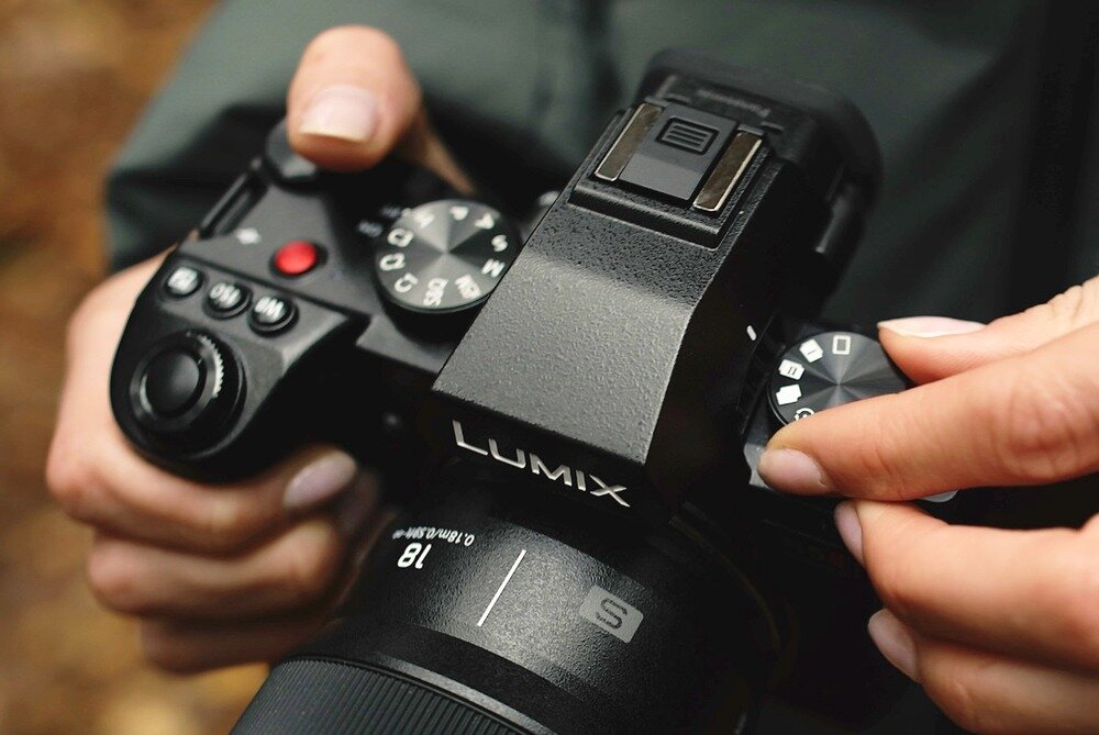 Aparat PANASONIC DC-S5M2E człowiek obsługuje pokrętła  