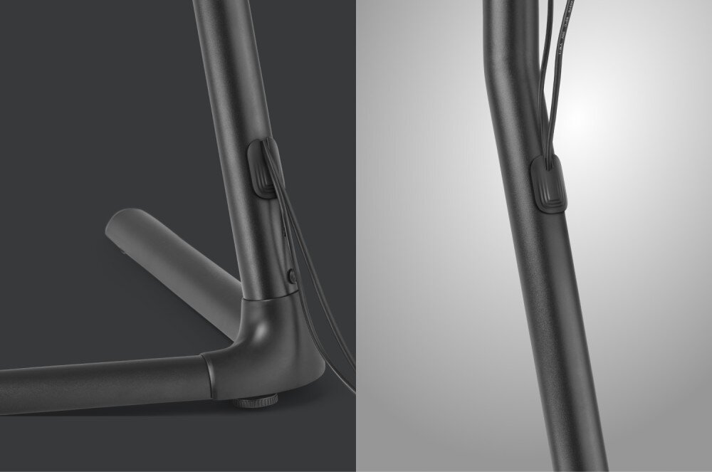 Stojak podłogowy ONE FOR ALL Zestawienie dwóch zbliżeń na nogę stojaka wykonaną z ciemnego metalu. Na obu ujęciach widać gumowy lub plastikowy uchwyt zamocowany do rury, przez który przechodzą czarne przewody elektryczne, co pozwala na ich uporządkowanie wzdłuż konstrukcji