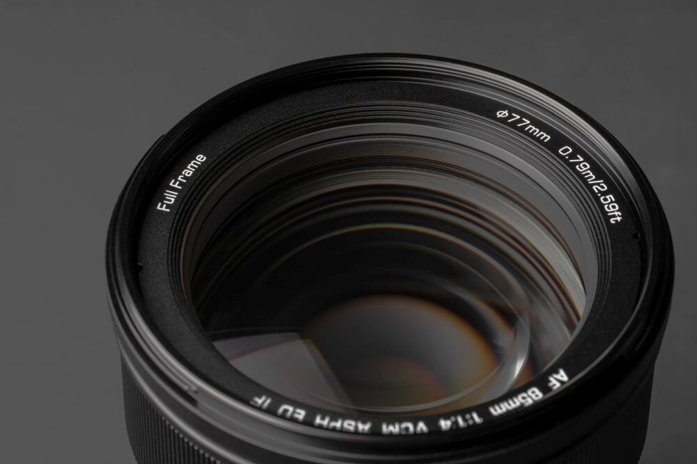 Obiektyw fotograficzny z widocznymi napisami: \'Full Frame\', \'Ø77mm 0.79m/2.59ft\', \'AF 85mm f/1.4 VDM VXM ED IF\'.