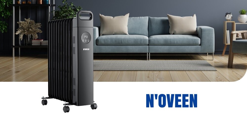 Grzejnik olejowy N\'OVEEN stoi na drewnianej podłodze w salonie z niebieską sofą i poduszkami. Na dole widoczny jest napis \'N\'OVEEN\'.