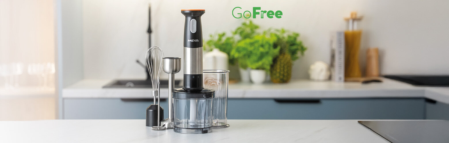 Akumulatorowy blender ręczny CMBL-01 na kuchennym blacie z przystawkami, pojemnikiem do siekania i pojemnikiem z miarką.