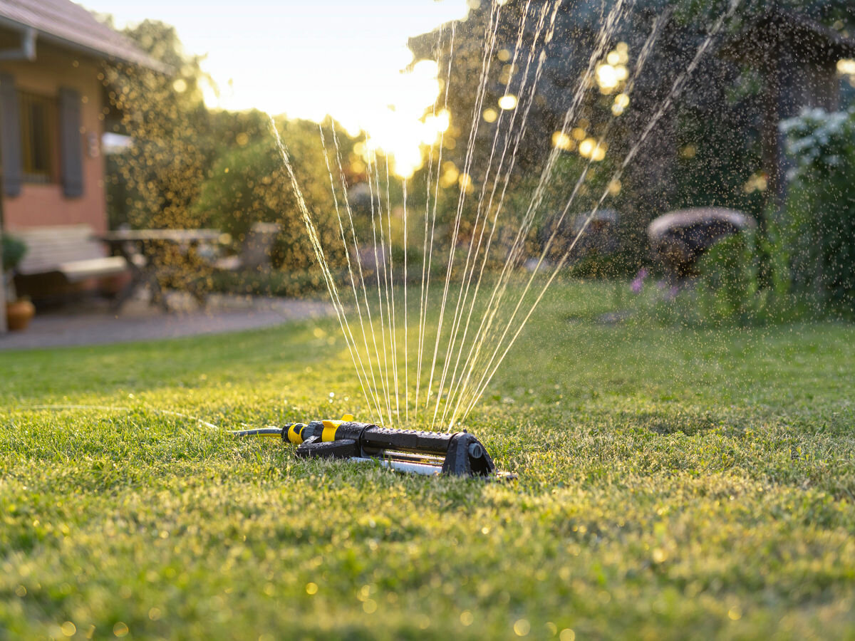 Zraszacz KARCHER OS 5.320 SV, Regulacja, Zraszacz, dopasowanie, nawadnianie, w tle ogród i dom, zachód słońca, na pierwszym planie zraszacz pracujący w ogrodzie