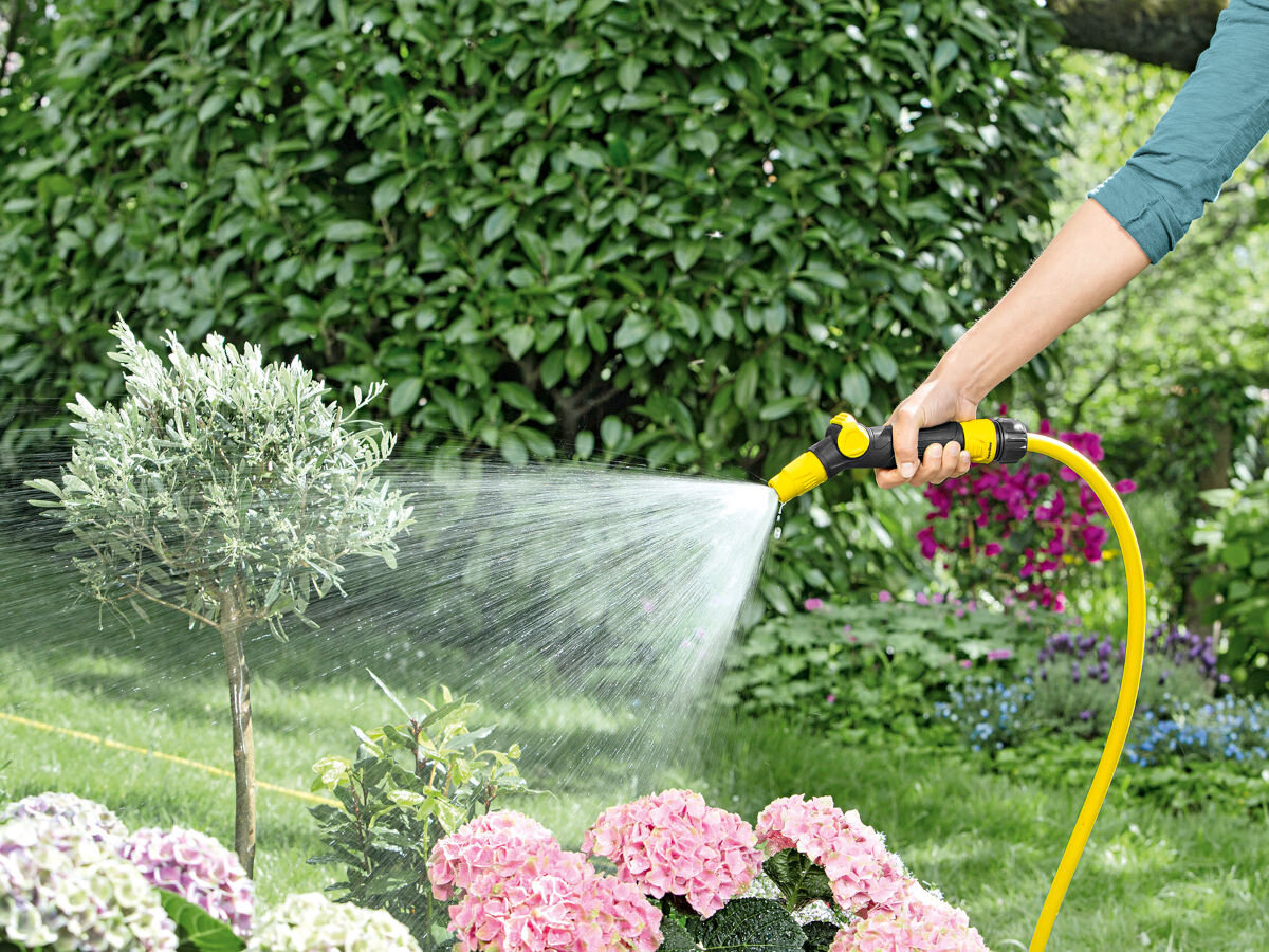 Wąż ogrodowy KARCHER PrimoFlex 1/2 50 m 2.645-139.0, substancje, ftalany, bar, ołów, ekologia, w tle ogród, dłoń trzyma wąż karcher podlewający rośliny w ogrodzie