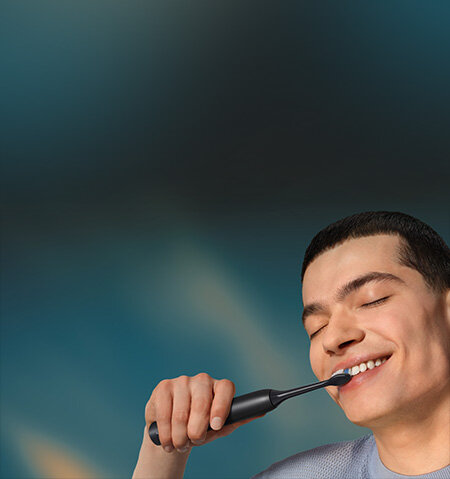 Grafika przedstawiająca zbliżenie na twarz mężczyzny myjącego zęby szczoteczką soniczną.