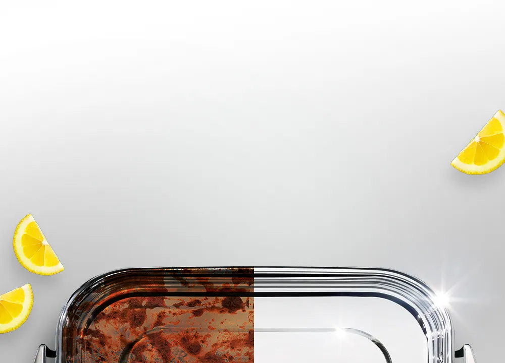 Blacha do pieczenia w połowie z zaschniętym brudem, w połowie czysta i błyszcząca, obok kawałki cytryny.