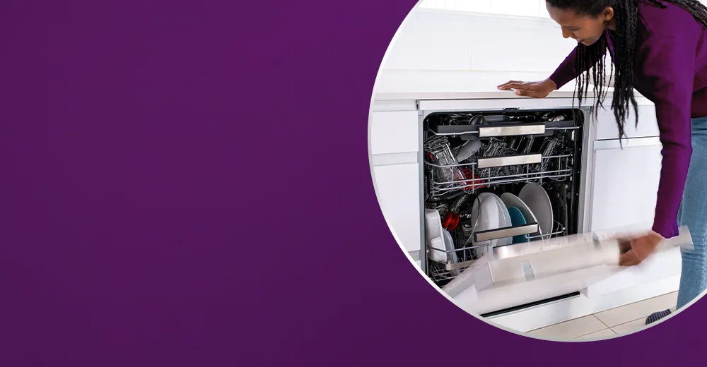 Kobieta otwierająca zmywarkę z naczyniami w białej kuchni.