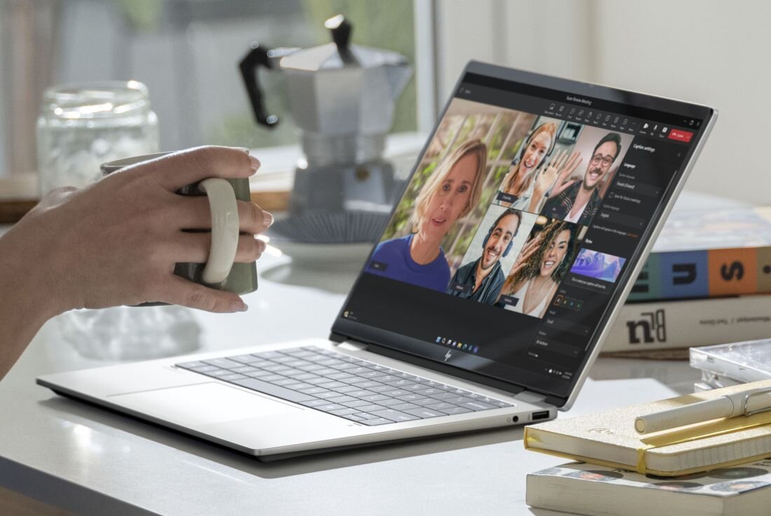 Wideokonferencja na laptopie HP OmniBook na kuchennym blacie, w tle akcesoria i notatniki.