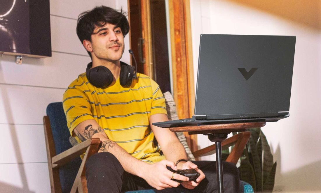 Laptop HP Victus 15 - Mężczyzna w słuchawkach, siedzący na krześle, korzysta z laptopa. Pojemna bateria, HP Fast Charge  