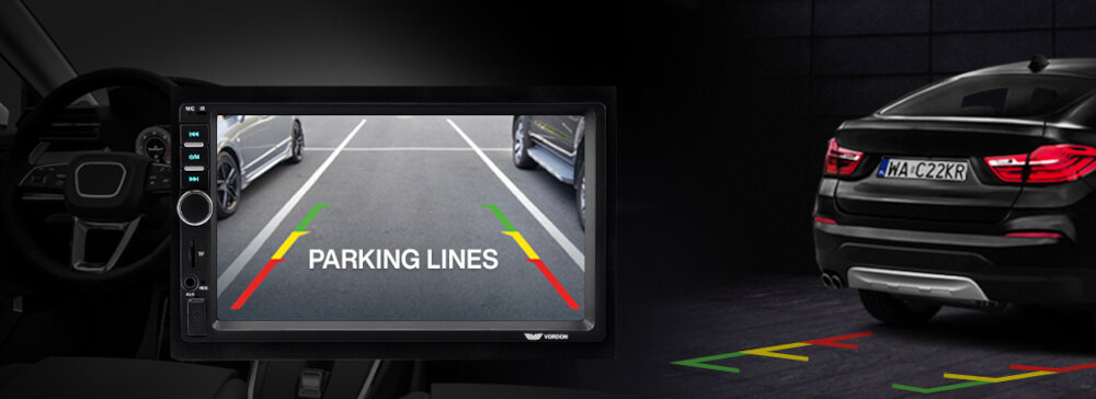 Obraz przedstawia ekran radia samochodowego z widokiem kamery cofania i liniami parkingowymi w kolorach zielonym, żółtym i czerwonym. Obok widoczny jest tył czarnego samochodu z tablicą rejestracyjną MA-CZ22KR oraz linie parkingowe na podłożu.