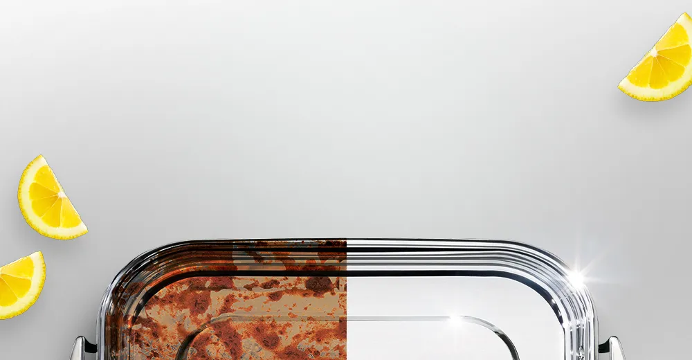 Blacha do pieczenia w połowie z zaschniętym brudem, w połowie czysta i błyszcząca, obok kawałki cytryny.