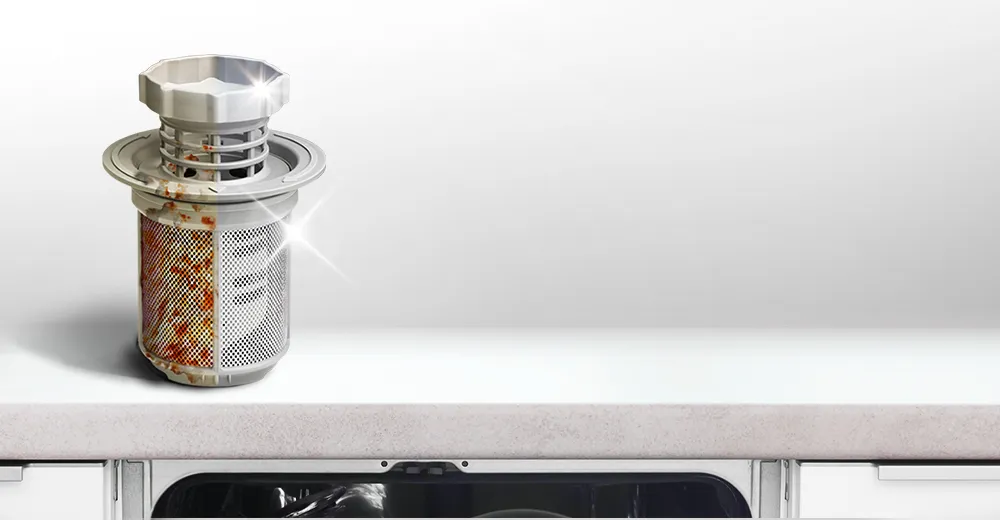 Filtr zmywarki w połowie zabrudzony tłuszczem i resztkami jedzenia, w połowie czysty i błyszczący.