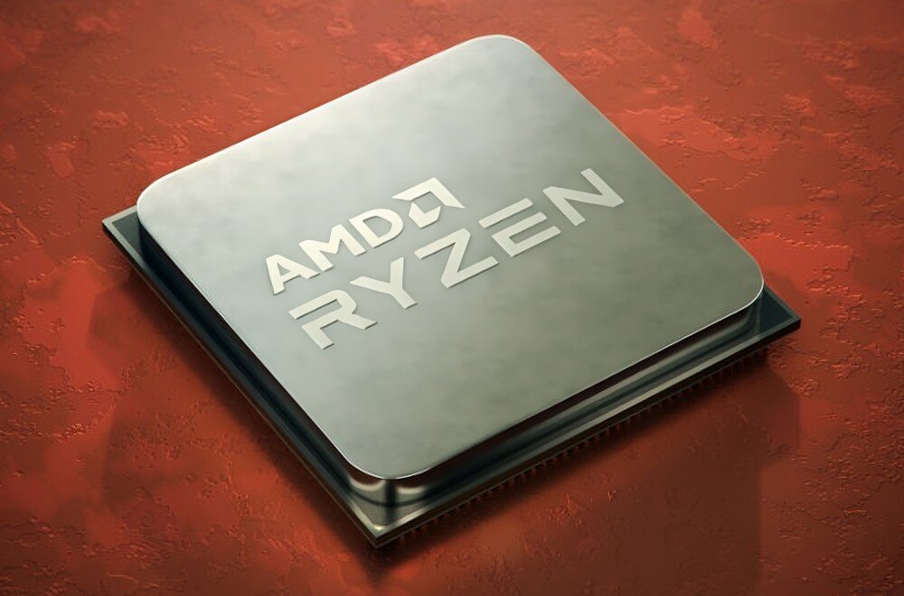 Na obrazie widoczny jest procesor z logo \'AMD RYZEN\' na metalicznej powierzchni, umieszczony na czerwonym tle.