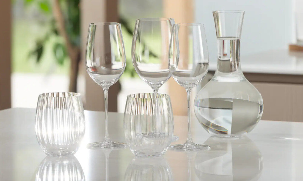 ZMYWARKA MIELE G 5811 SCi Active Plus CS Zdjęcie przedstawia zestaw eleganckich szklanek, kieliszków i karafkę ustawionych na gładkiej, błyszczącej powierzchni blatu. Przejrzyste szkło i naturalne światło podkreślają czystość oraz wysoką jakość wykonania naczyń świeża woda 6 litrów 0,52 kWh program ECO niskie zużycie