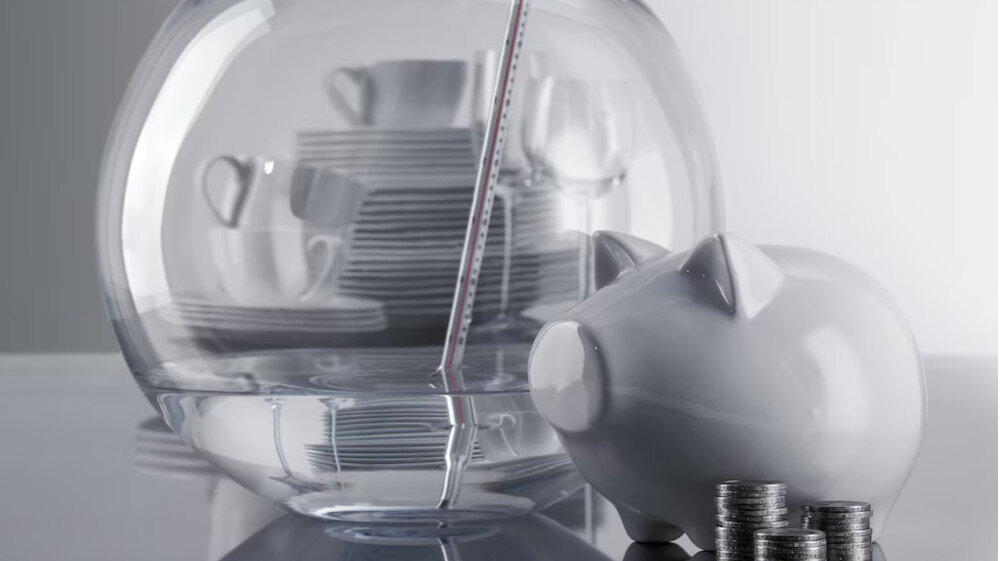 ZMYWARKA MIELE G 5862 SCVi Active Plus S Zdjęcie przedstawia szklaną kulę wypełnioną uporządkowaną zastawą stołową, obok której stoi ceramiczna skarbonka w kształcie świnki. Ujęcie symbolicznie podkreśla oszczędność oraz efektywne gospodarowanie zasobami, sugerując niższe koszty eksploatacji ECO oszczędność wody oszczędność energii program ekonomiczny