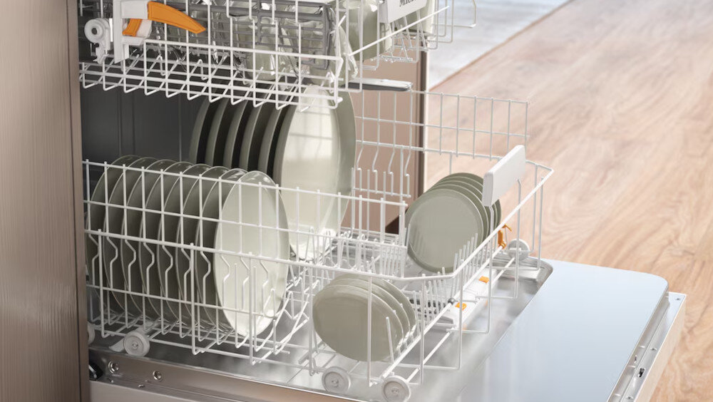 ZMYWARKA MIELE G 5862 SCVi Active Plus S Zdjęcie przedstawia otwartą zmywarkę z wysuniętymi koszami, w których starannie ułożono talerze o różnych rozmiarach. Jasne światło i przejrzysty układ naczyń podkreślają pojemność urządzenia oraz wygodę organizacji miejsca wewnątrz Comfort szuflada na sztućce regulacja wysokości elastyczne kosze MultiComfort