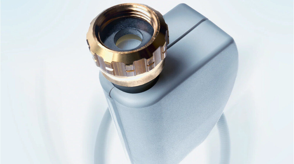 ZMYWARKA MIELE G 5862 SCVi Active Plus S Zdjęcie przedstawia element instalacyjny z metalową nakrętką, najprawdopodobniej będący częścią systemu dopływu wody, takim jak wąż przyłączeniowy urządzenia AGD. Ujęcie podkreśla solidne wykonanie z połączenia tworzywa i metalu, sugerując trwałość i bezpieczeństwo użytkowania Waterproof System WPS podwójny zawór ochrona przed zalaniem bezpieczeństwo