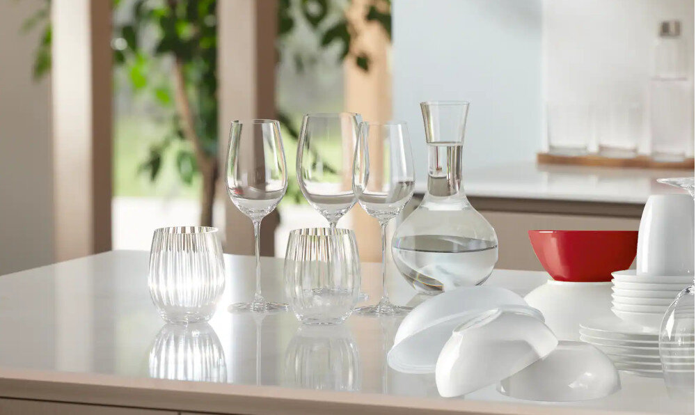 ZMYWARKA MIELE G 7040 SCi AutoDos CS Zdjęcie przedstawia zestaw kieliszków, szklanek oraz karafkę z wodą ustawionych na jasnym, lśniącym blacie kuchennym. Naturalne światło wpadające przez okno podkreśla przejrzystość szkła oraz tworzy elegancką, harmonijną aranżację stołu SensorDry inteligentne suszenie ochrona mebli czujnik temperatury optymalizacja programu mniejsze zużycie energii krótszy czas