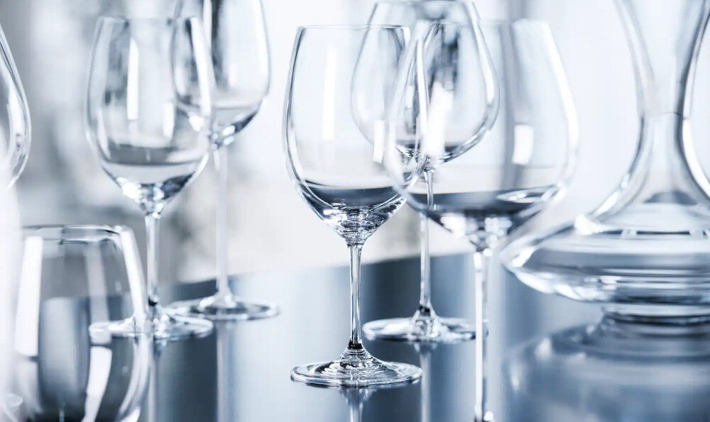 ZMYWARKA MIELE G7085 SCVI XXL Zdjęcie przedstawia eleganckie kieliszki i szklanki ustawione na połyskującej powierzchni, odbijającej ich kształty i światło. Kompozycja podkreśla przejrzystość szkła oraz jego wysoką jakość, tworząc wrażenie luksusu i czystości dodatkowe suszenie wyższa temperatura suche szkło suche plastiki