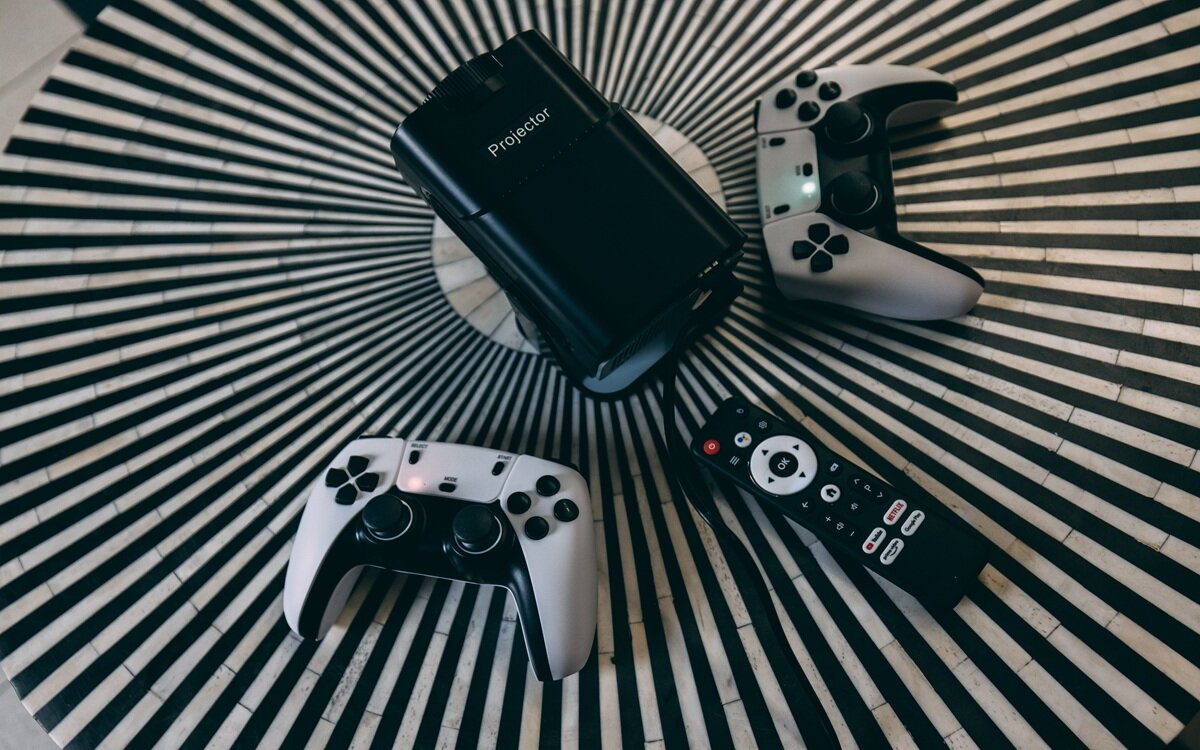 EXTRALINK GG400X Android 11 aplikacji multimedialnych, serwisów streamingowych i gier sklepowi Google Play - projektor, kontrolery i pilot na stoliku