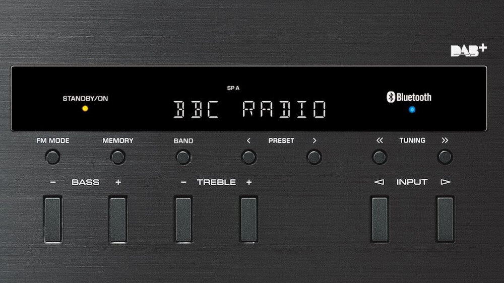 Panel przedni urządzenia audio z wyświetlaczem pokazującym \'BBC RADIO\'. Widoczne przyciski do regulacji basów, tonów wysokich, wyboru pasma i trybu FM, a także logo DAB+ i Bluetooth.