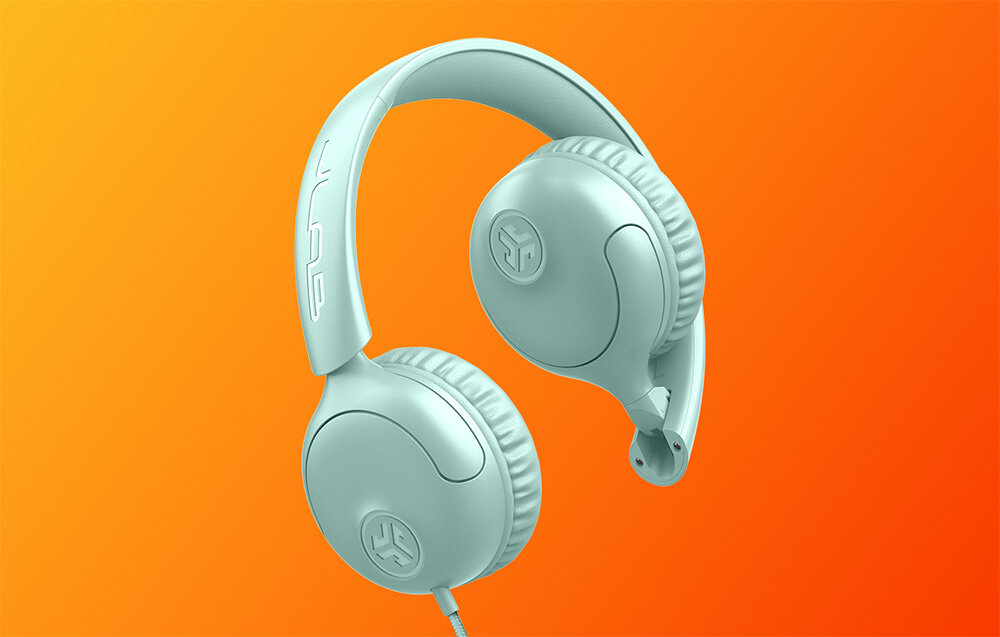 Słuchawki nauszne JLAB Studio 2 mikrofon pilot sterowanie rozmowy kontrola muzyki przewodowe, Błękitne słuchawki nauszne z logotypem na obudowie, ukazane w locie na jaskrawym tle