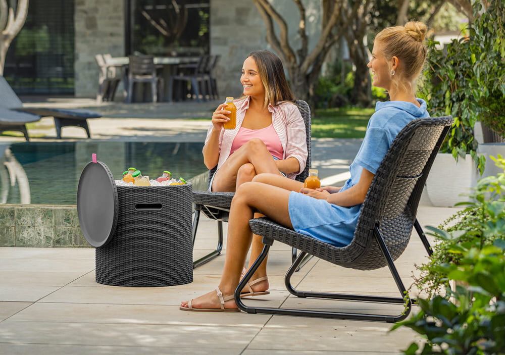 Stolik ogrodowy KETER Cool Stool 230905 z funkcją schowka Antracytowy taras stolik na tarasie dwie osoby siedzą na fotelach ogrodowych w tle dom i rośliny praktyczne rozwiązanie wielofunkcyjny mebel cztery stolik siedzisko lodówka schowek