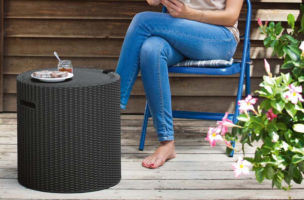 Stolik ogrodowy KETER Cool Stool 230905 z funkcją schowka Antracytowy taras osoba siedzi na krześle obok stolik na stoliku talerz i słoik faktura inspirowana rattanem komponuje się z meblami ogrodowymi przyjemna w dotyku łatwa do czyszczenia waga około 4 kg uchwyty