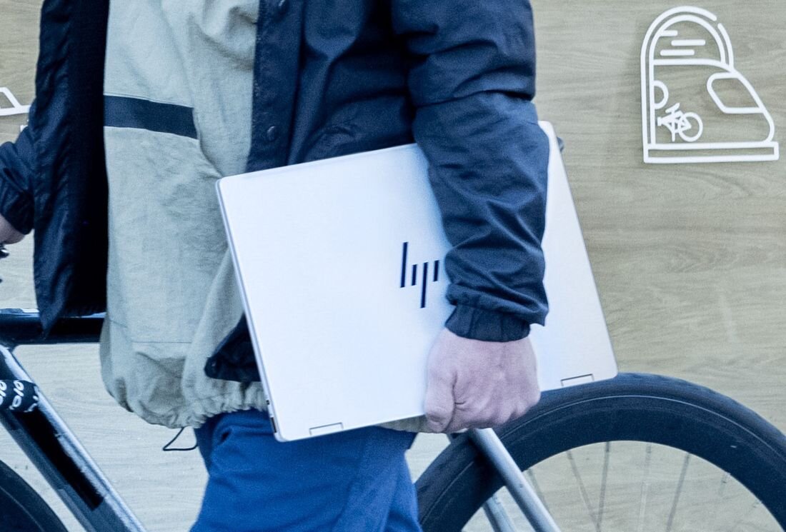 Mężczyzna z laptopem HP OmniBook oraz rowerem, scena przed wejściem do kawiarni z charakterystycznym oznaczeniem rowerowym. - Kompaktowa konstrukcja, wymiary Piaskowane, anodyzowane wykończenie  