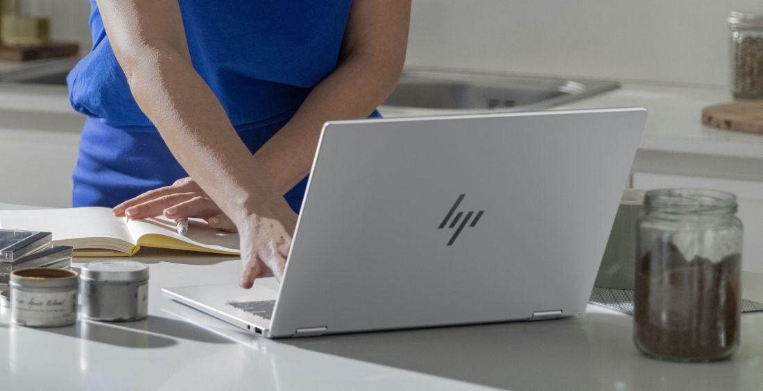 Użytkowniczka korzystająca z laptopa HP OmniBook w jasnej kuchni, na blacie widoczne słoiki oraz notatnik. - dysk SSD PCIe Gen4 NVMe M.2  