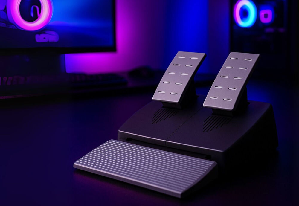 Kierownica FR-TEC Racing Wheel BL7002 PS5/PC zbliżenie na pedały na ciemnym blacie w tle monitor komputer oraz akcesoria komputerowe poświata kolorowych ledów zestaw pedałów gaz hamulec dozowanie przyspieszenia i siły hamowania