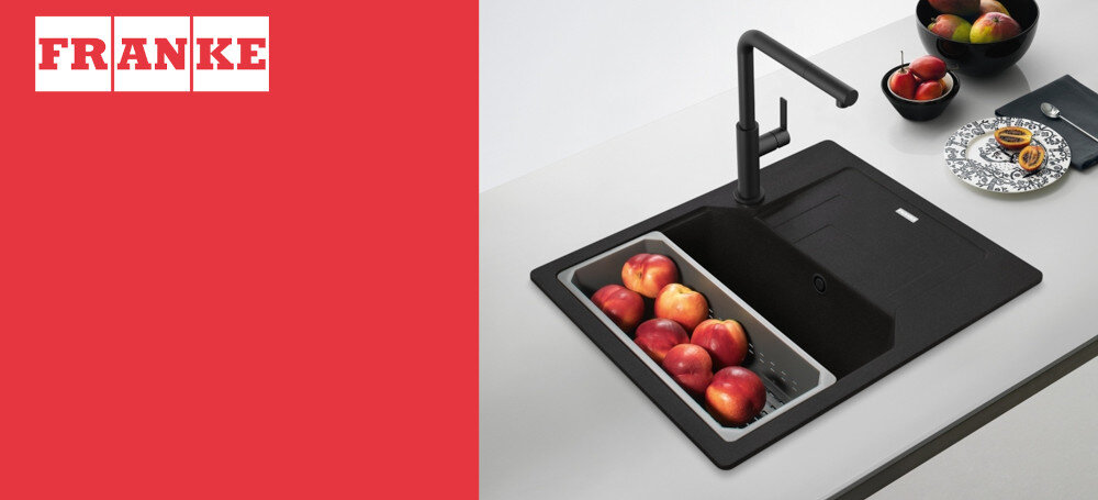 ZLEWOZMYWAK FRANKE Urban UBG 611-62 114.0741.207 Zlewozmywak Franke zamontowany w jasnym blacie kuchennym z czarną baterią stojącą. Po lewej stronie widoczne jest logo FRANKE na czerwonym tle
