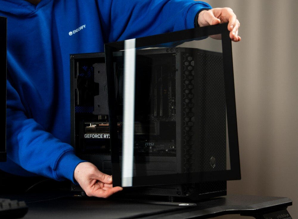 Obudowa ENDORFY Signum M30 Air Osoba trzymająca w dłoniach panel z hartowanego szkła podczas montowania go na boku czarnej obudowy