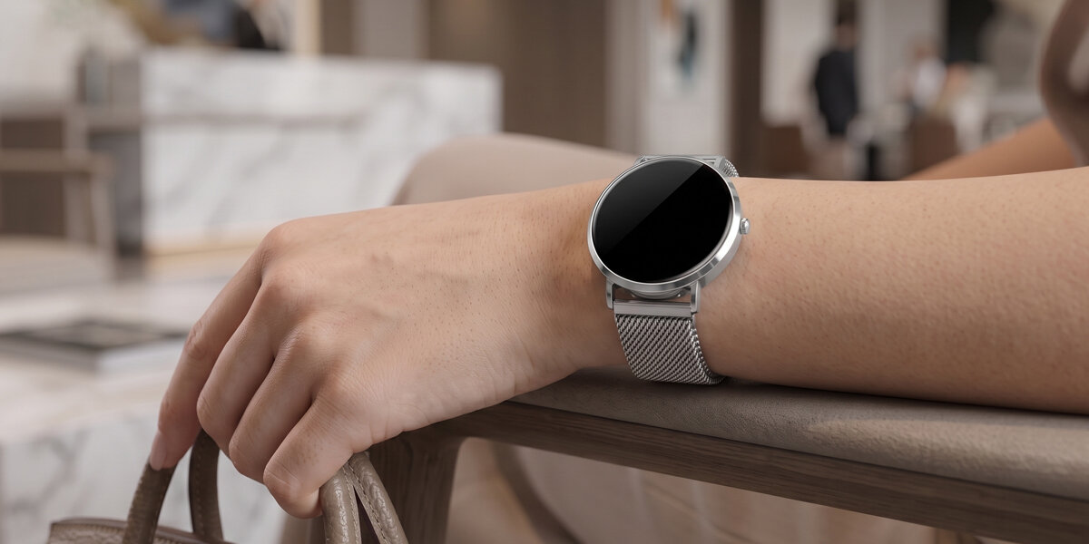 Kobieta trzyma torebkę. Na jej nadgarstku znajduje się srebrny smartwatch Denver z wygaszonym, czarnym ekranem.