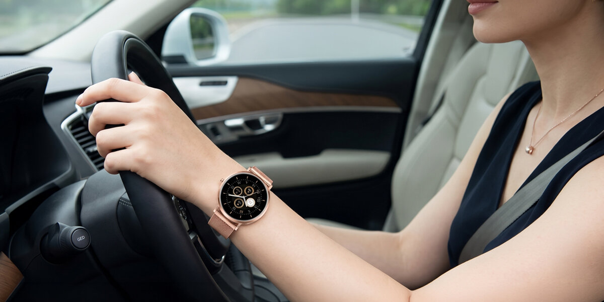 Kobieta trzyma dłoń na kierownicy samochodu. Na jej nadgarstku znajduje się smartwatch Denver z czarną tarczą.
