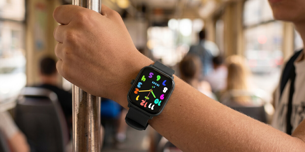 Nastolatek trzyma się poręczy w tramwaju, mając na ręku czarny smartwatch Denver z kolorową tarczą i krokomierzem.