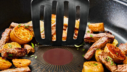 Zbliżenie na powłokę Fusion Core patelni TEFAL Excellence+ G3301902, na niej jedzenie i czarna łopatka kuchenna.