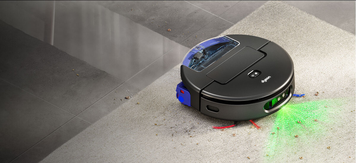 Robot stoi na dywanie i zbiera suche zabrudzenia. Za nim widać umyte płytki podłogowe