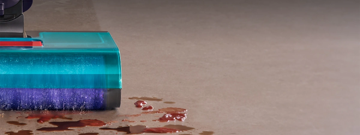 Zbliżenie na prawą stronę szczotki mopa podczas pracy. Wałek zbiera zabrudzenia, okruchy i myje plamy na podłodze