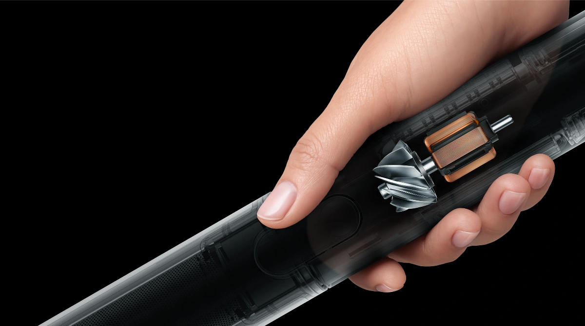 Osoba trzyma w dłoni odkurzacz, który częściowo jest pokazany w przekroju z wyraźnie zaznaczonym silnikiem