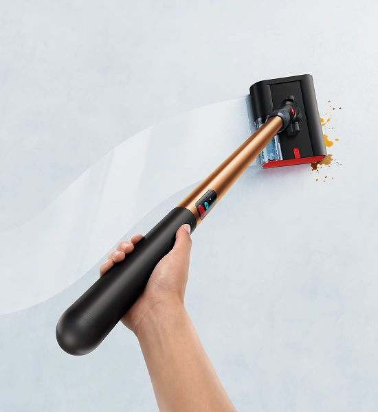 W ujęciu od góry widać mop w kobiecej dłoni. Za mopem jest nieregularny lśniący ślad świeżo umytej podłogi