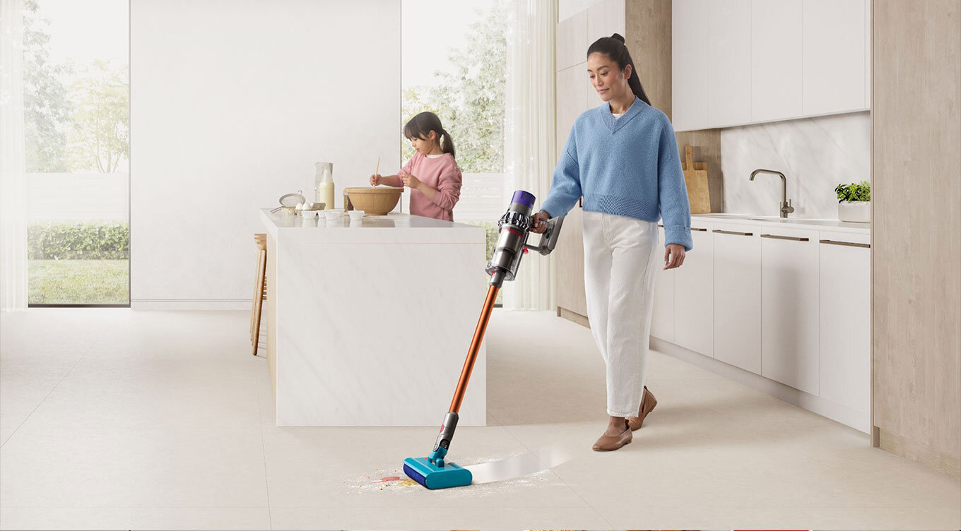 Modelka zmywa brudną podłogę w kuchni odkurzaczem Dyson V10 Submarine z końcówką do mycia podłóg