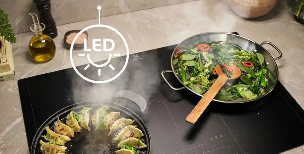 Oświetlone potrawy na płycie prześ światło z okapu