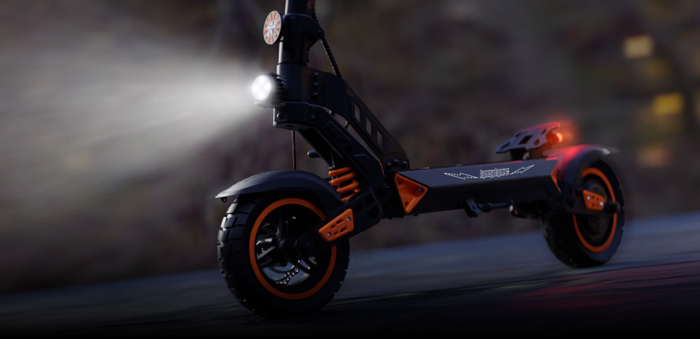 Hulajnoga elektryczna KAMIKAZE K1 60km 1000W 10 cali Czarny droga ulica ciemność zbliżenie na podest przednia lampa się świeci przednie i tylne światło LED praktyczne kierunkowskazy wbudowane w podest jasna lampa z przodu efektowne podświetlenie platformy bezpieczeństwo łatwe i czytelne sygnalizowanie zmiany kierunku