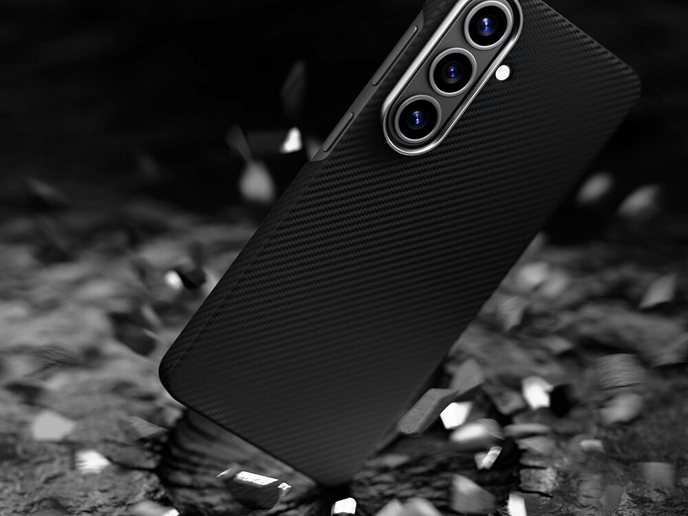 Smartfon Samsung Galaxy S w etui z włókna aramidowego upadający na ziemię, efekt kruszącego się podłoża sugerujący wysoką odporność na uderzenia